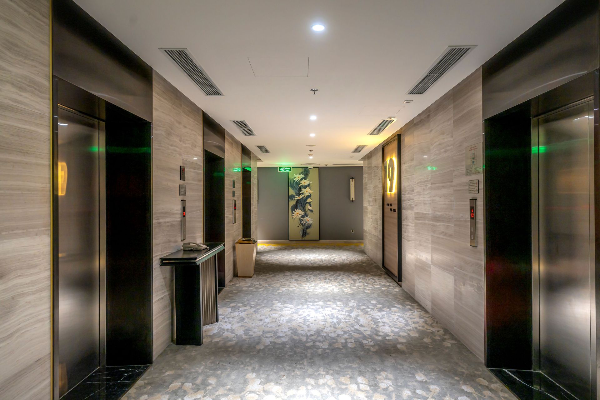 Spacious hotel hallway with elevators and contemporary decor.